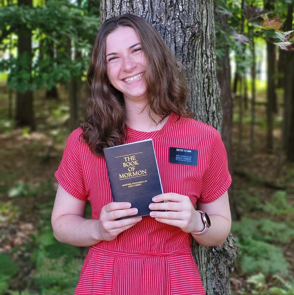 A person in a red dress holding a book in front of a tree

AI-generated content may be incorrect.