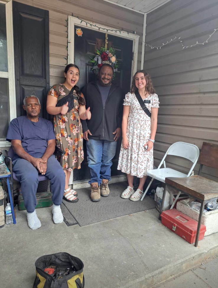 A group of people standing in front of a house

AI-generated content may be incorrect.